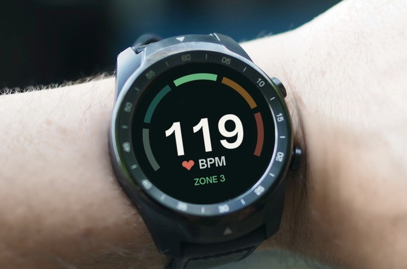 Sport watch on a wrist showing 119 BPM in a five-zone heart rate display